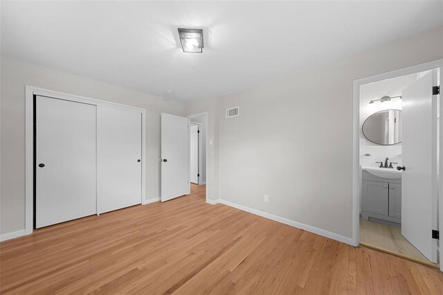 1865 Shardell Dr, Spanish Lake Township, MO 63138 - unfurnished bedroom with light wood finished floors, a sink, baseboards, a closet, and connected bathroom