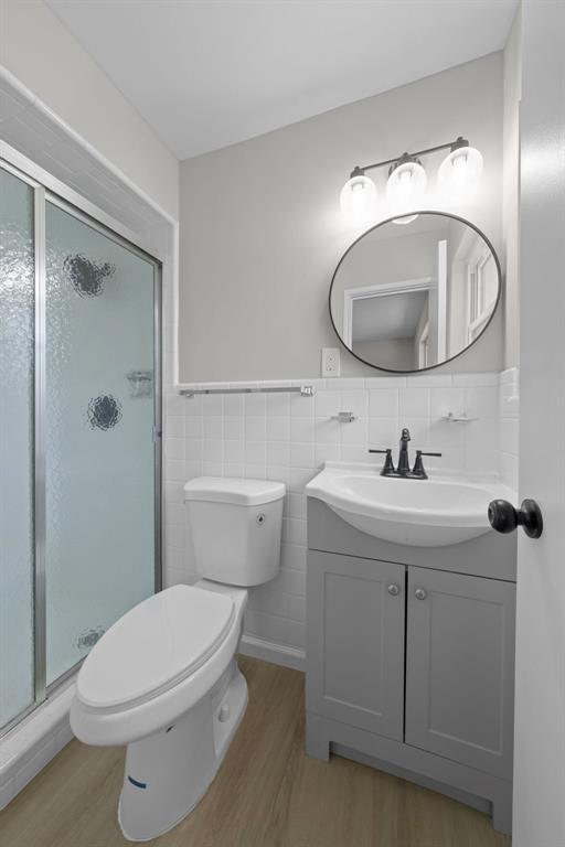 1865 Shardell Dr, Spanish Lake Township, MO 63138 - bathroom with wood finished floors, vanity, toilet, a stall shower, and tile walls