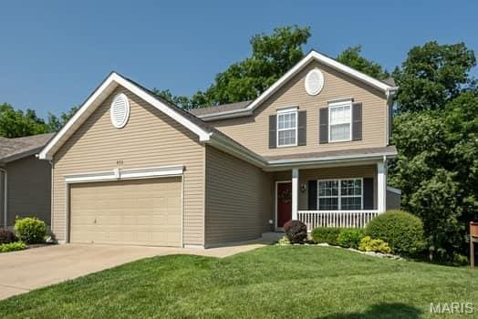 538 Springhurst Pkwy, Ofallon, MO 63368 - traditional-style house featuring an attached garage, a porch, concrete driveway, and a front lawn