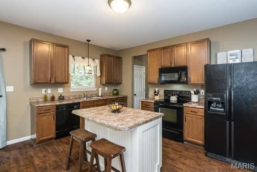 538 Springhurst Pkwy, Ofallon, MO 63368 - kitchen featuring black appliances, a kitchen breakfast bar, dark wood-style floors, and light countertops