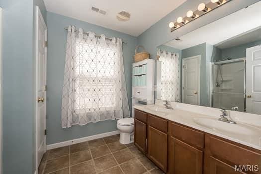 538 Springhurst Pkwy, Ofallon, MO 63368 - full bathroom with double vanity, an enclosed shower, toilet, baseboards, and tile patterned flooring