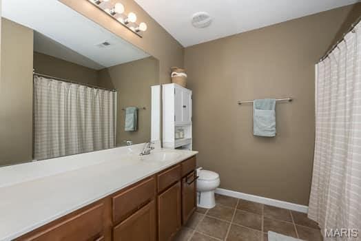 538 Springhurst Pkwy, Ofallon, MO 63368 - bathroom with vanity, toilet, tile patterned flooring, baseboards, and curtained shower