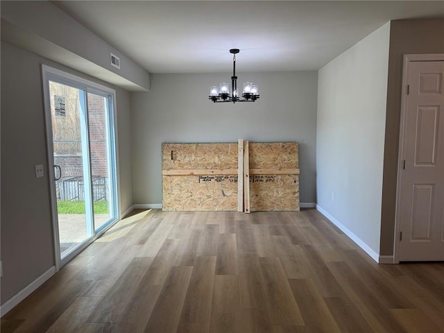 3624 Market St, Saint Louis, MO 63115 - unfurnished dining area with a chandelier, baseboards, wood finished floors, and healthy amount of natural light