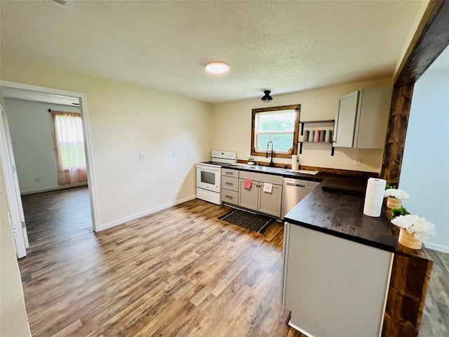 108 Gray St, Sullivan, MO 63080 - kitchen with white range oven, dark countertops, stainless steel dishwasher, a sink, and light wood finished floors