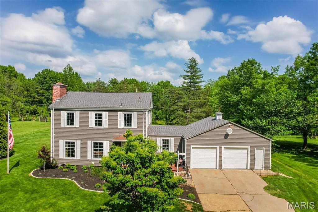 11 S Weldon Springs Heights Dr, Weldon Spring, MO 63304 - colonial home with a chimney, a garage, driveway, a front lawn, and a shingled roof