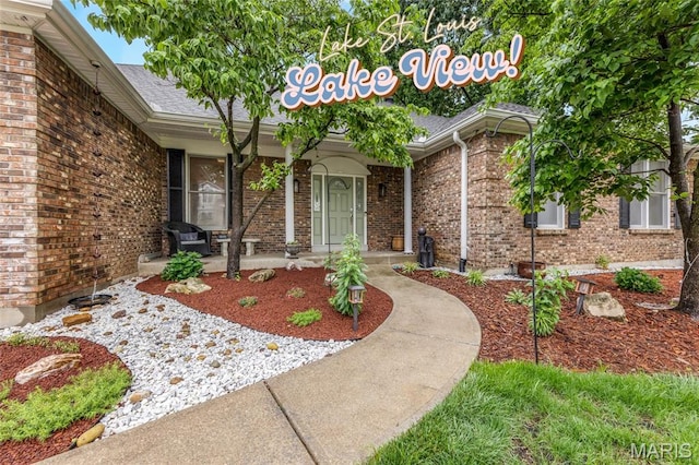 15 Eagles Way Ln, Lake St Louis, MO 63367 - doorway to property featuring brick siding, a porch, and roof with shingles