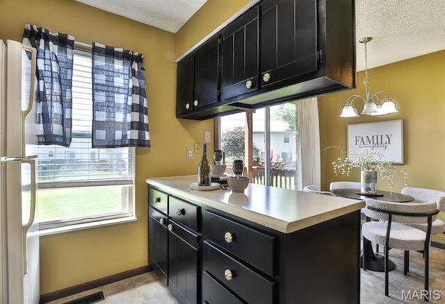 2223 Highland Hill Drive E, Saint Peters, MO 63376 - kitchen with dark cabinets, a textured ceiling, a peninsula, a chandelier, and light countertops