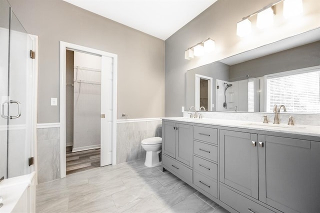 3 Wedgewood Ct, Edwardsville, IL 62025 - bathroom featuring tile walls, a shower stall, double vanity, a wainscoted wall, and a walk in closet