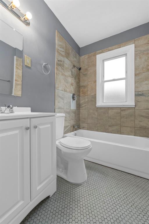 7348 Grand Dr, Pagedale, MO 63133 - bathroom featuring toilet, vanity, washtub / shower combination, and tile patterned flooring