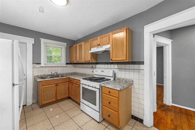 7348 Grand Dr, Pagedale, MO 63133 - kitchen featuring under cabinet range hood, white appliances, a sink, light countertops, and backsplash