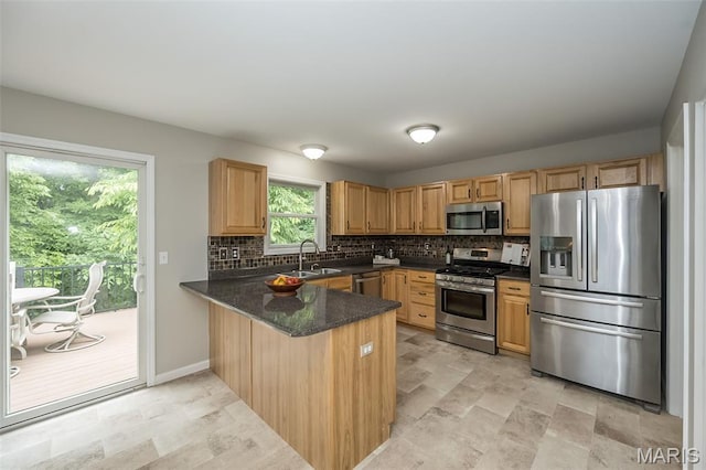 3414 Bedford Falls Dr, Wentzville, MO 63385 - kitchen featuring appliances with stainless steel finishes, a peninsula, a sink, decorative backsplash, and stone finish flooring