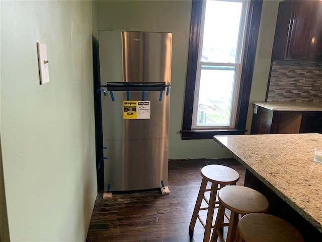 201 3rd St, Chaffee, MO 63740 - kitchen with freestanding refrigerator, dark wood-type flooring, a kitchen breakfast bar, backsplash, and dark brown cabinetry