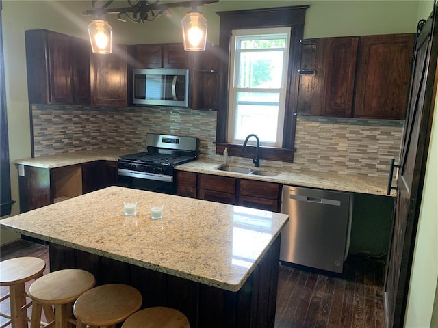 201 3rd St, Chaffee, MO 63740 - kitchen featuring stainless steel appliances, a sink, a breakfast bar area, dark wood-style floors, and a kitchen island
