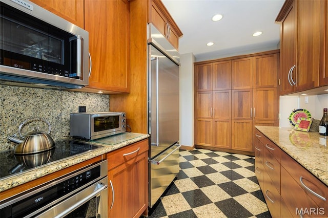 816 S Hanley Rd Unit 8C, Saint Louis, MO 63105 - kitchen featuring appliances with stainless steel finishes, dark flooring, decorative backsplash, brown cabinetry, and recessed lighting