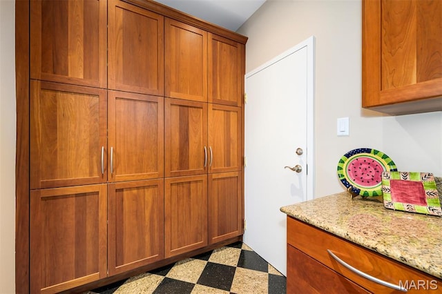 816 S Hanley Rd Unit 8C, Saint Louis, MO 63105 - kitchen with tile patterned floors, brown cabinets, and light stone counters