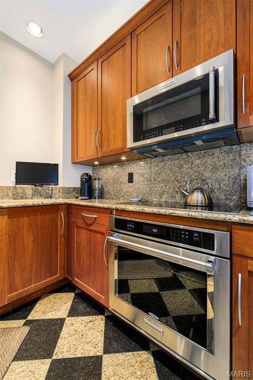 816 S Hanley Rd Unit 8C, Saint Louis, MO 63105 - kitchen featuring stainless steel appliances, recessed lighting, light stone counters, granite tiled floors, and tasteful backsplash