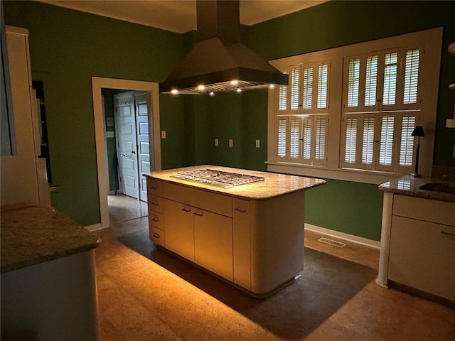 301 N Everett St, Kennett, MO 63857 - kitchen with stainless steel gas cooktop, island exhaust hood, baseboards, and white cabinets