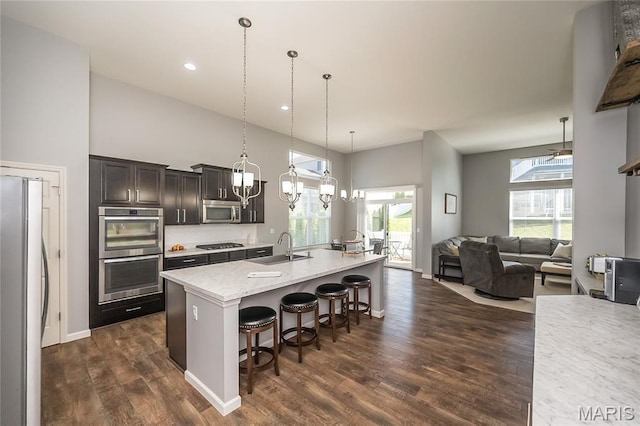 1510 Kennabrooke Ct, Saint Louis, MO 63146 - kitchen featuring stainless steel appliances, a breakfast bar area, dark wood-style floors, an island with sink, and open floor plan