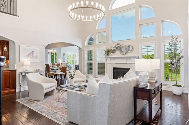 5360 Tower Hill Ct, Weldon Spring, MO 63304 - living area featuring a chandelier, arched walkways, a high ceiling, dark wood-style floors, and a glass covered fireplace