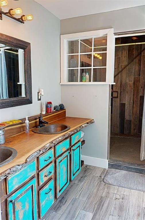 3828 Peters Ford Rd, Leslie, MO 63056 - bathroom featuring a stall shower, double vanity, and wood finished floors