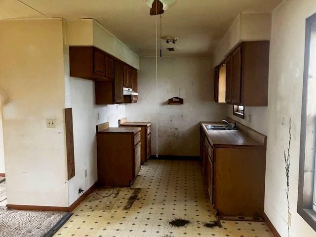 506 W Main St, Matthews, MO 63867 - kitchen featuring light flooring, under cabinet range hood, a sink, and dark countertops