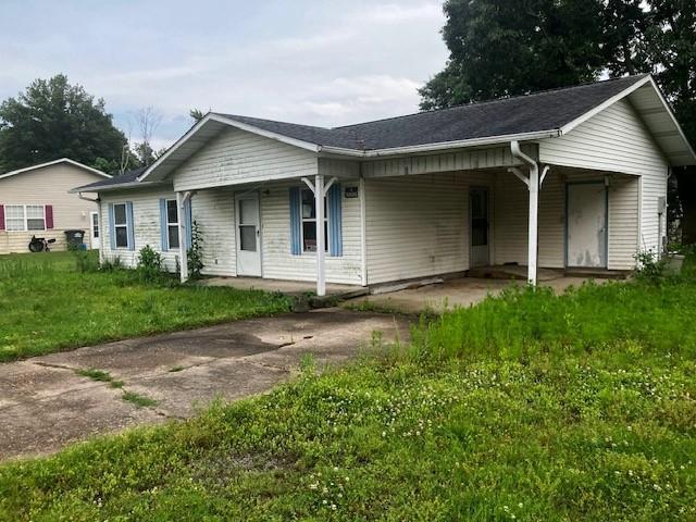 506 W Main St, Matthews, MO 63867 - ranch-style home with concrete driveway, a carport, a front lawn, and covered porch