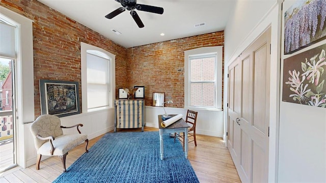 1107 N 2nd St, Saint Charles, MO 63301 - living area with plenty of natural light, light wood-type flooring, a ceiling fan, brick wall, and a wainscoted wall