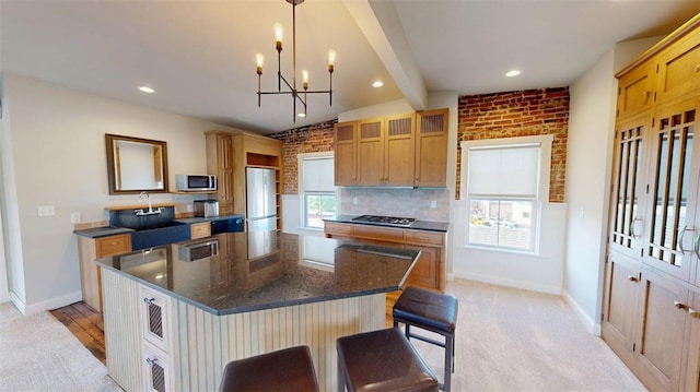 1107 N 2nd St, Saint Charles, MO 63301 - kitchen with stainless steel appliances, a chandelier, a kitchen island, dark stone countertops, and baseboards