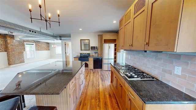 1107 N 2nd St, Saint Charles, MO 63301 - kitchen with stainless steel appliances, light wood-type flooring, a chandelier, tasteful backsplash, and dark stone counters
