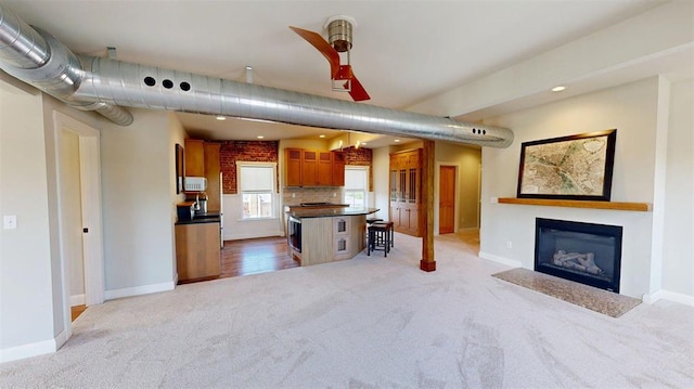 1107 N 2nd St, Saint Charles, MO 63301 - kitchen with light carpet, brown cabinetry, dark countertops, a glass covered fireplace, and recessed lighting