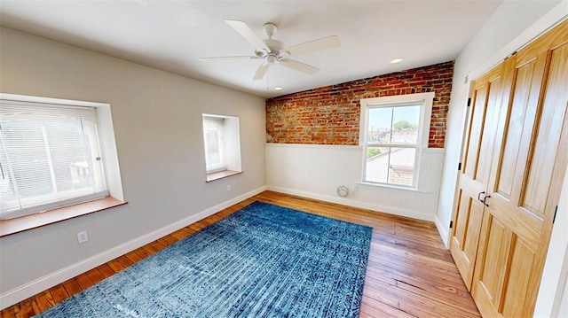 1107 N 2nd St, Saint Charles, MO 63301 - unfurnished room with wainscoting, a ceiling fan, light wood finished floors, baseboards, and brick wall