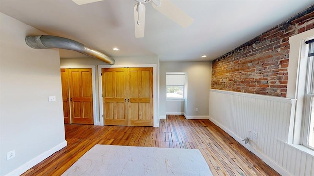 1107 N 2nd St, Saint Charles, MO 63301 - unfurnished bedroom featuring hardwood / wood-style flooring, wainscoting, brick wall, a closet, and recessed lighting