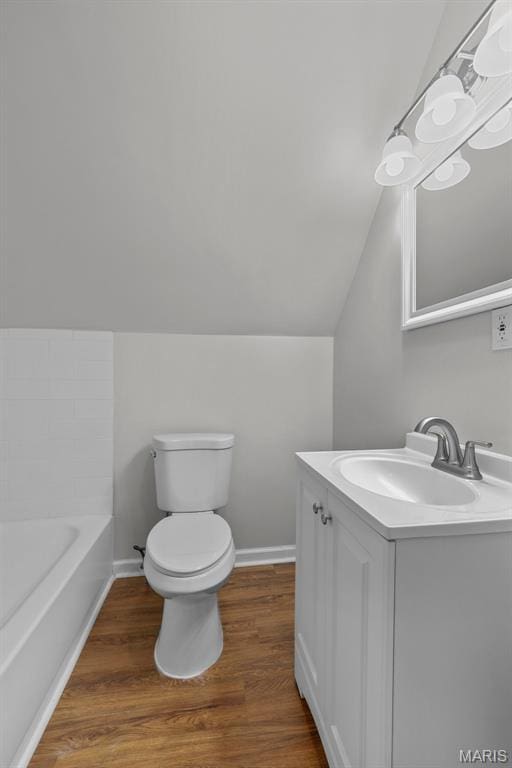 6014 Westminster Pl, Saint Louis, MO 63112 - bathroom with vanity, lofted ceiling, toilet, a tub to relax in, and wood finished floors
