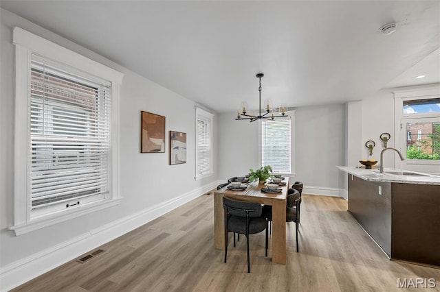 6014 Westminster Pl, Saint Louis, MO 63112 - dining area with light wood-type flooring, a chandelier, and baseboards