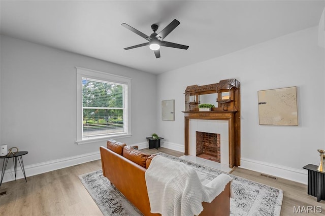 6014 Westminster Pl, Saint Louis, MO 63112 - living room with wood finished floors, ceiling fan, a tiled fireplace, and baseboards