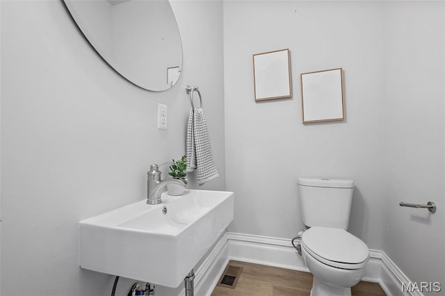6014 Westminster Pl, Saint Louis, MO 63112 - bathroom with toilet, a sink, wood finished floors, and baseboards