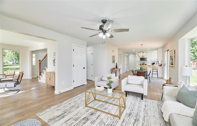 7219 Watsons Parish Dr, Ofallon, MO 63368 - living area with stairway, light wood-type flooring, ceiling fan, and baseboards