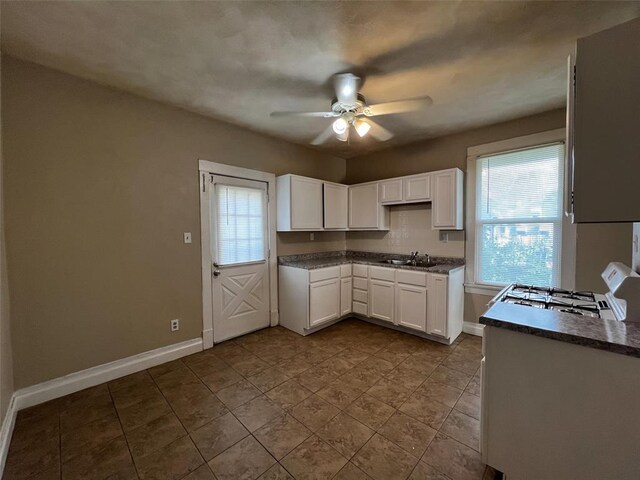 1638 Poplar St, Granite City, IL 62040 - kitchen featuring white gas range oven, a sink, ceiling fan, dark countertops, and white cabinets