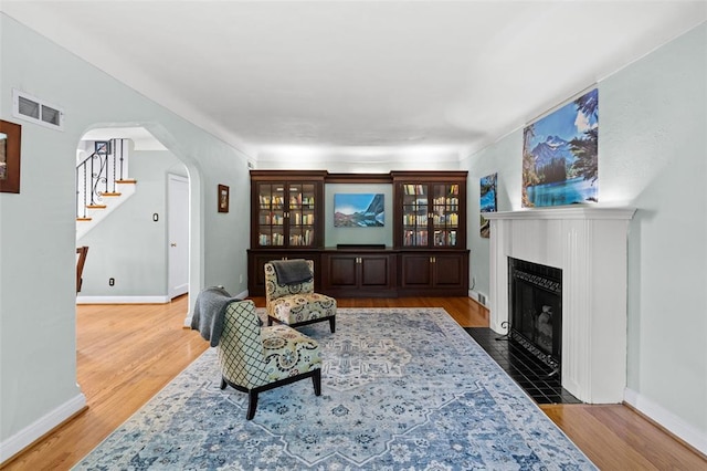 8145 University Dr, Clayton, MO 63105 - living room with arched walkways, a fireplace with flush hearth, stairs, and baseboards
