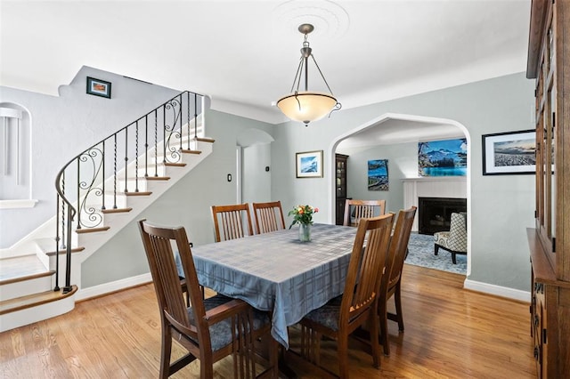 8145 University Dr, Clayton, MO 63105 - dining space with arched walkways, light wood-type flooring, stairs, and baseboards