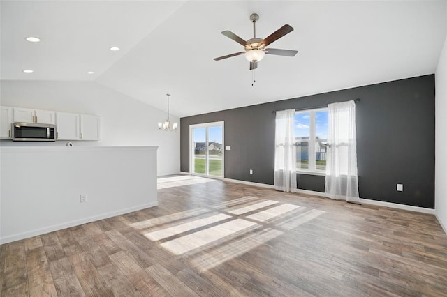 917 Gimli Ln, Wright City, MO 63390 - unfurnished living room with vaulted ceiling, a chandelier, ceiling fan, light wood-style flooring, and baseboards