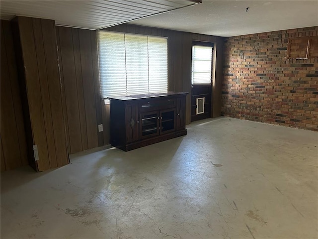 2 Graham Dr, Union, MO 63084 - unfurnished living room with unfinished concrete flooring, brick wall, and wood walls