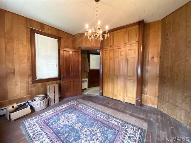 405 W 18th St, Hermann, MO 65041 - unfurnished bedroom featuring wood walls, hardwood / wood-style floors, radiator, a chandelier, and a closet