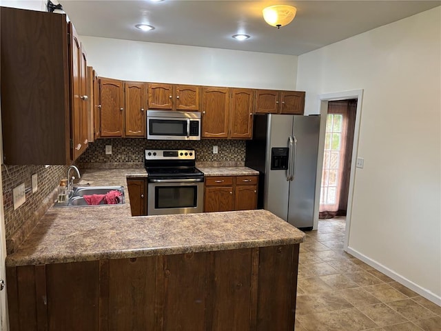 603 Capps Ave, Nokomis, IL 62075 - kitchen with appliances with stainless steel finishes, a sink, baseboards, decorative backsplash, and a peninsula