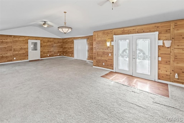 21604 Fox Dr, Carlyle, IL 62231 - unfurnished living room with a ceiling fan, french doors, vaulted ceiling, wooden walls, and carpet flooring