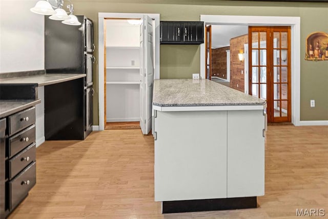 21604 Fox Dr, Carlyle, IL 62231 - kitchen featuring light wood-type flooring, dark cabinetry, a peninsula, freestanding refrigerator, and french doors