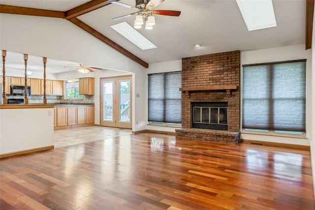 1101 Claycrest Dr, Cottleville Township, MO 63304 - unfurnished living room featuring a skylight, a ceiling fan, light wood finished floors, and a fireplace