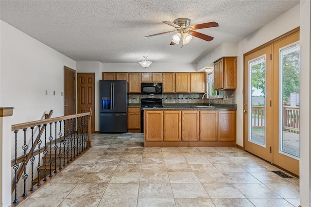 1101 Claycrest Dr, Cottleville Township, MO 63304 - kitchen featuring black appliances, brown cabinets, dark countertops, decorative backsplash, and a textured ceiling