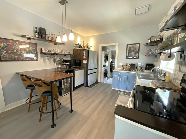 1509 Booker St, Hannibal, MO 63401 - kitchen featuring open shelves, stacked washer / drying machine, a sink, blue cabinetry, and freestanding refrigerator