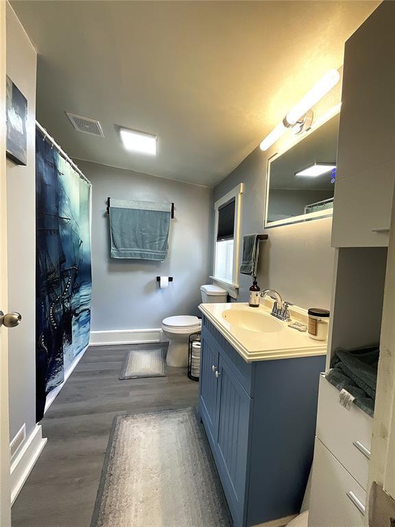 1509 Booker St, Hannibal, MO 63401 - bathroom featuring vanity, baseboards, wood finished floors, toilet, and curtained shower